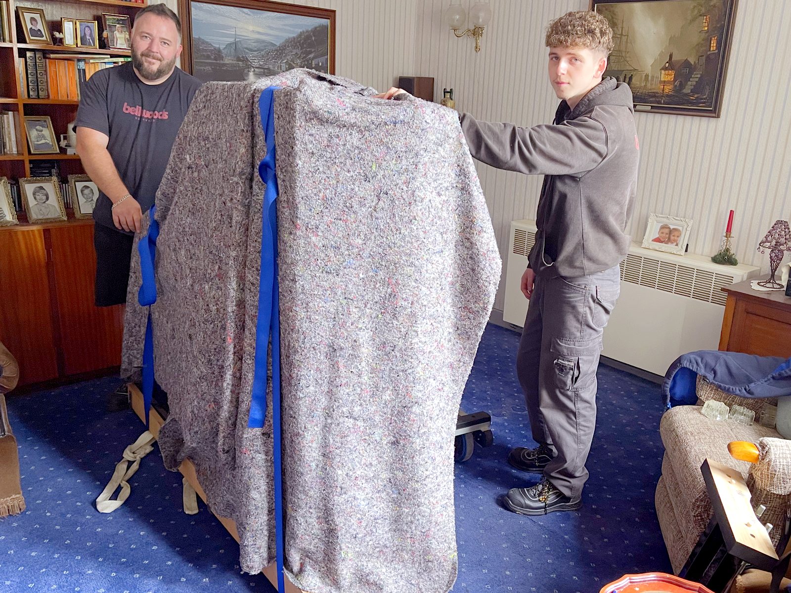 Grand piano on a slipper board, blanket wrapped and strapped, ready to go into storage