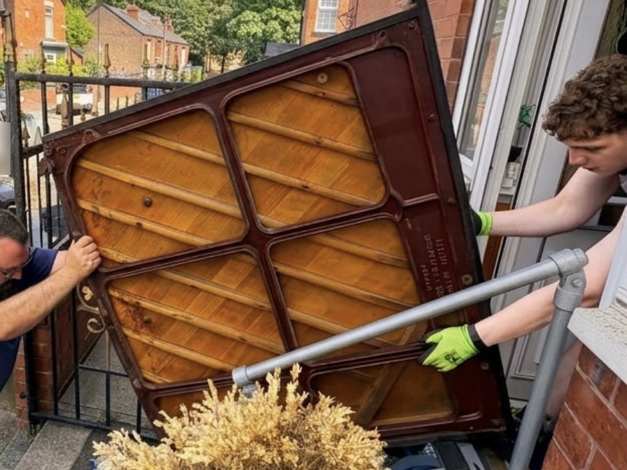 Upright piano being removed through a tight doorway for disposal in Barnsley
