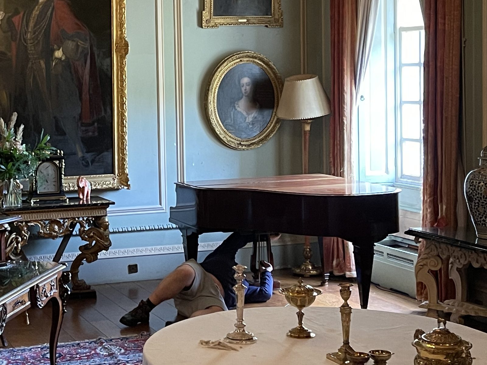 Grand piano being prepared for a move in a period drawing room