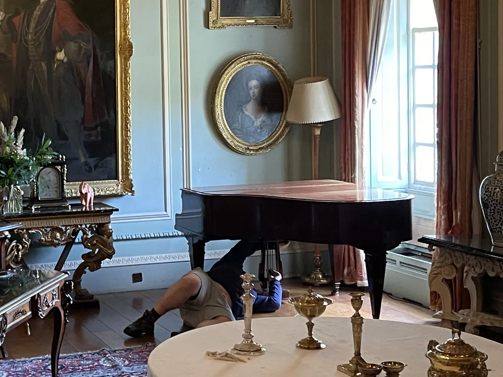 Grand piano being prepared for a move in a period drawing room