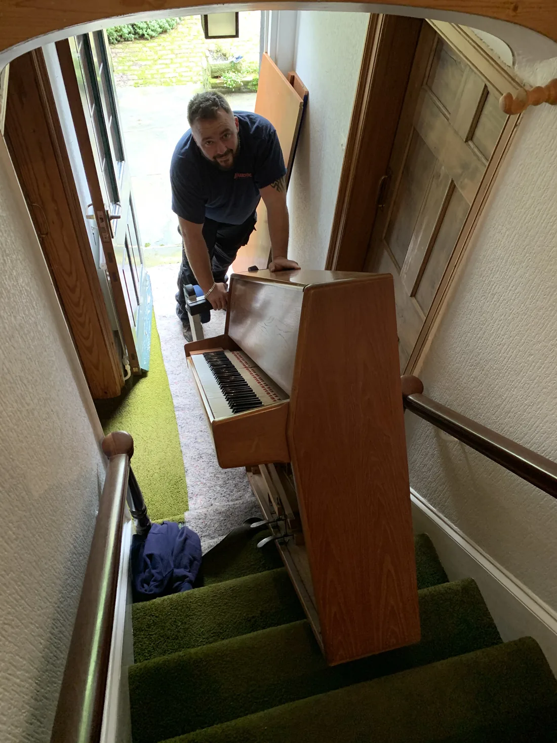 Upright piano being brought down a narrow domestic staircase