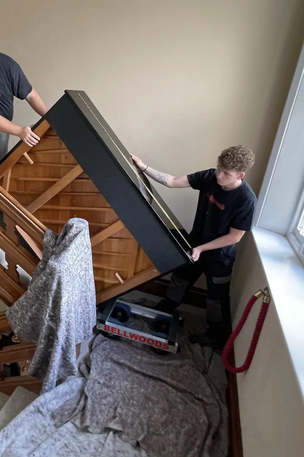 Piano being carried down a padded period staircase